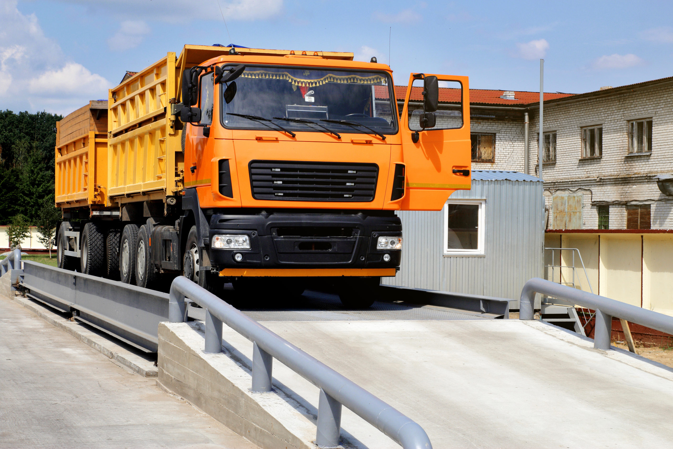 An orange truck with grain is weighed on the scales in the grain storage area Truck scales